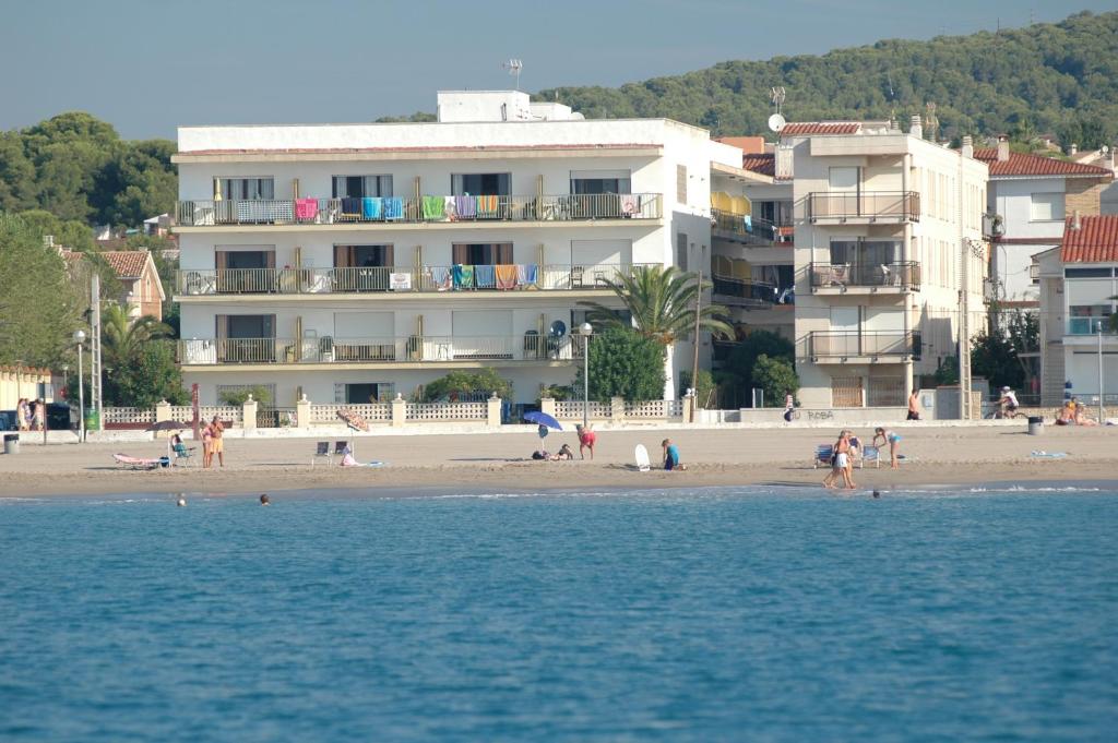 a beach with a building and people on the beach at Villa Service - Apartamentos Aransol in El Vendrell