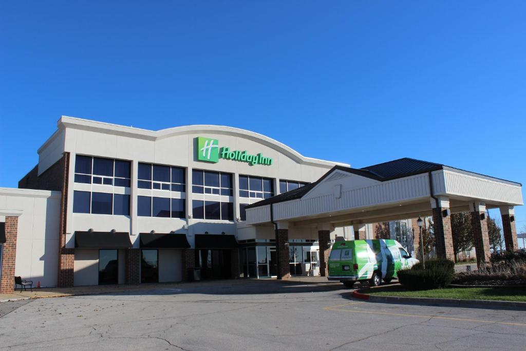 um edifício com uma carrinha verde estacionada em frente em Holiday Inn Des Moines-Airport Conf Center, an IHG Hotel em Des Moines