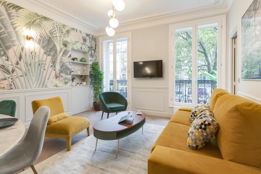 a living room with a couch and chairs and a tv at Stylish 2bd House in Central Paris by GuestReady in Paris
