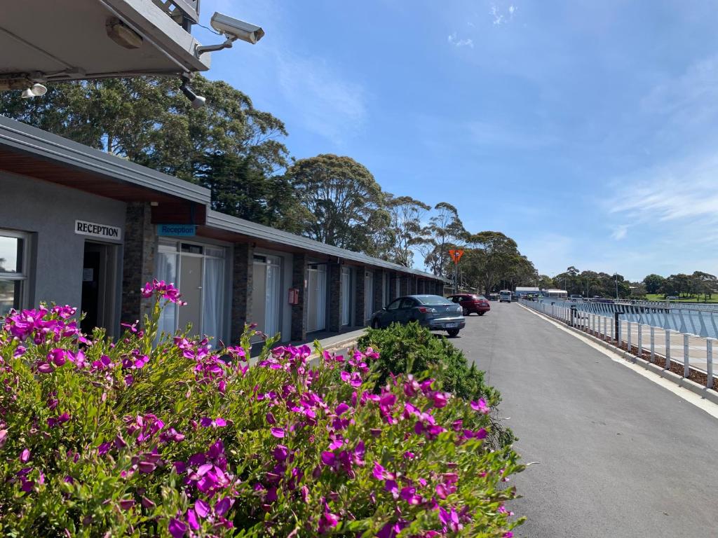 um edifício com flores roxas ao lado de uma estrada em The Waterfront Wynyard em Wynyard