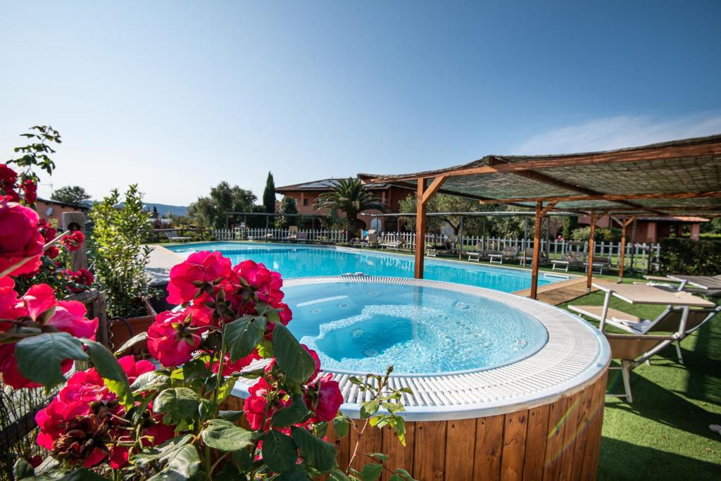 una bañera de hidromasaje en un jardín con flores rosas en Agriturismo Borgo Campetroso, en Suvereto