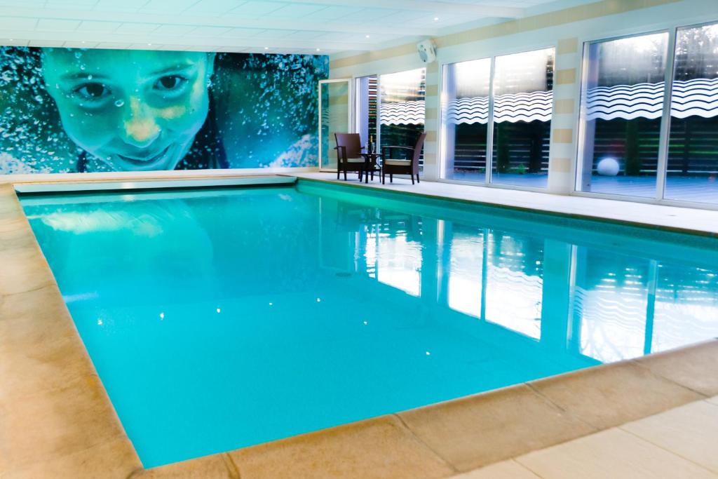ein Pool in einem Haus mit einem Gemälde an der Wand in der Unterkunft BRIT HOTEL CONFORT Saint-Brieuc Langueux in Langueux