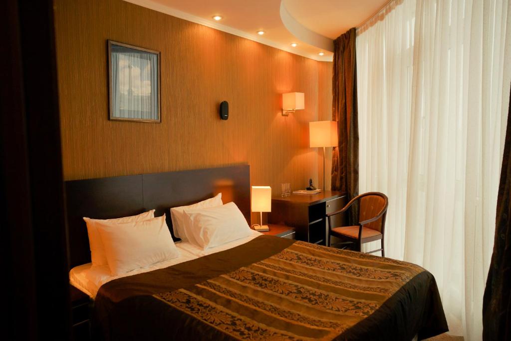 a hotel room with a bed and a desk and a window at Bogemia City Hotel in Saratov