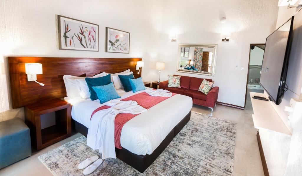 Cette chambre comprend un grand lit et une télévision. dans l'établissement Kruger Park Lodge Unit No. 610A, à Hazyview