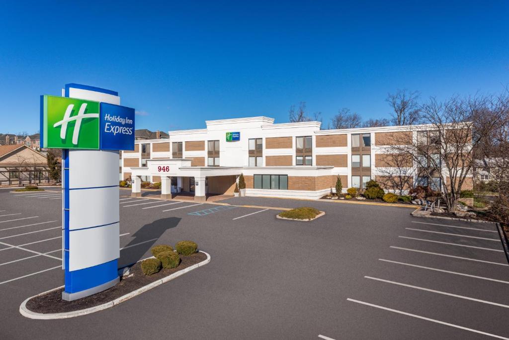 a building with a sign in front of a parking lot at Holiday Inn Express Ramsey Mahwah, an IHG Hotel in Ramsey