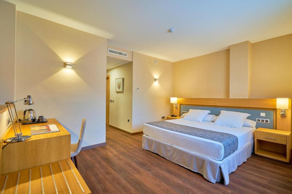 Habitación de hotel con cama grande y escritorio. en Hotel Guadalmedina, en Málaga