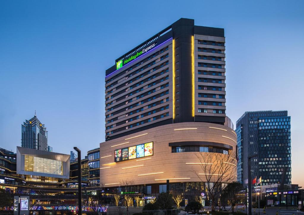 Holiday Inn Express Suzhou New District, an IHG Hotel في سوتشو: مبنى طويل في مدينة في الليل