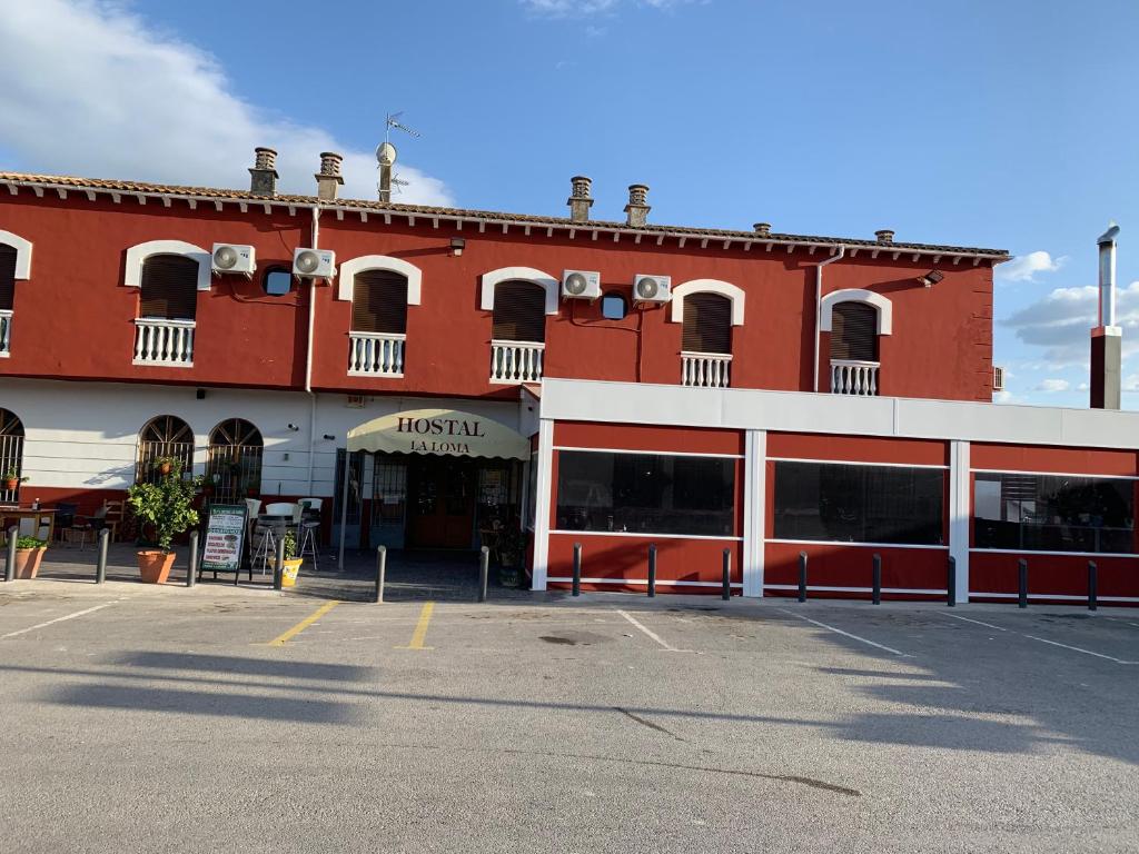 un aparcamiento vacío frente a un edificio rojo en Hotel-Restaurante la Loma, en Baeza