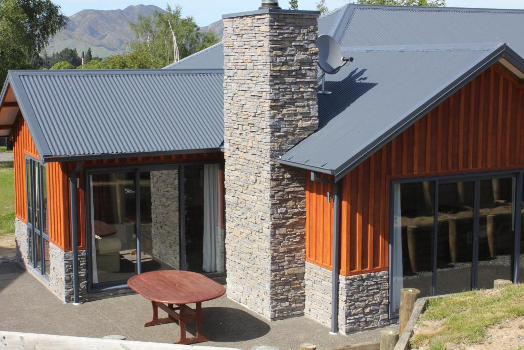 a house with a brick chimney and a bench at 3 Bellbird Place in Hanmer Springs