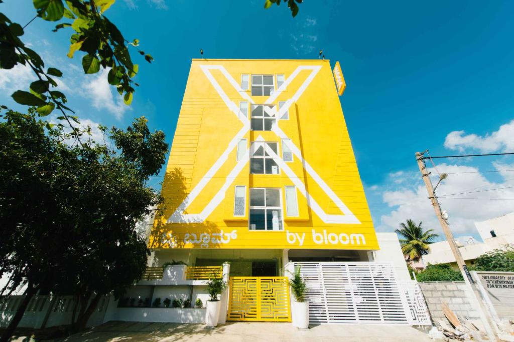 a yellow building with a sign that reads by bloom at X by Bloom I Hebbal Manyata Park in Bangalore