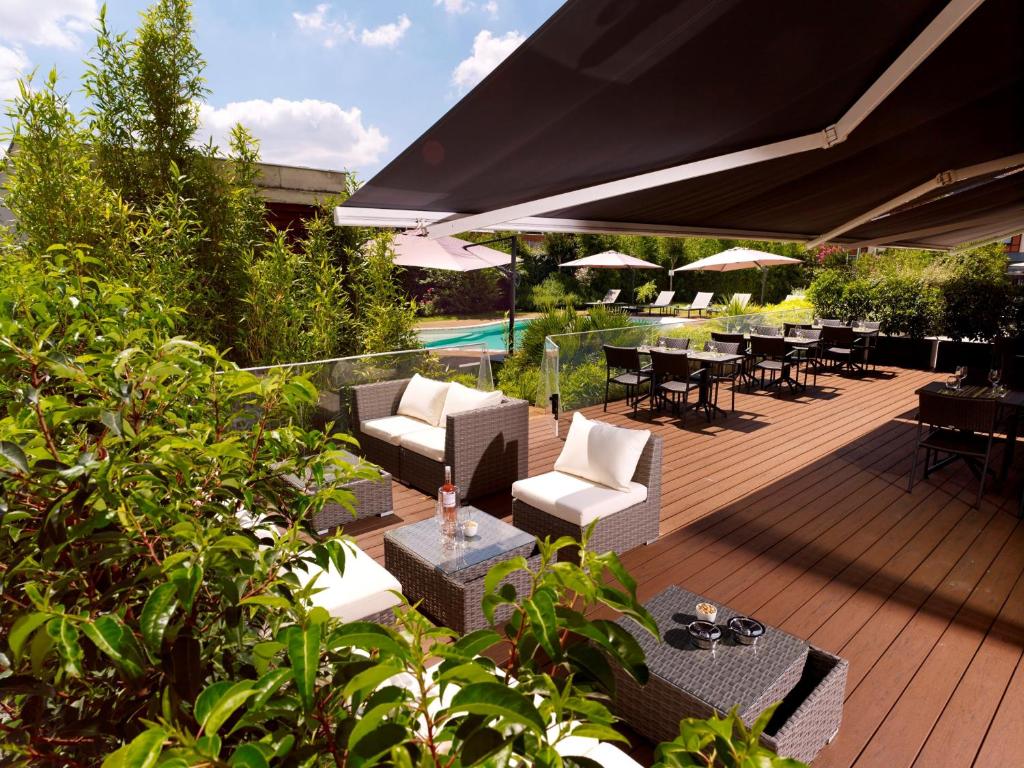 una terraza de madera con mesas, sillas y sombrilla en Holiday Inn Express Toulouse Airport, an IHG Hotel en Blagnac