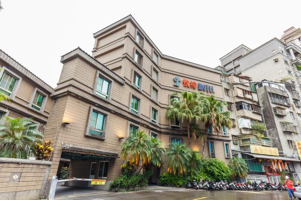 a building with palm trees in front of it at Love Tree Motel in Taipei