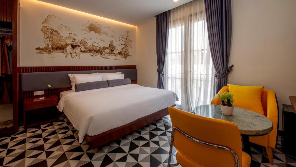 シェムリアップにあるThe Twizt - Lifestyle Hostelのベッドとテーブルが備わるホテルルームです。