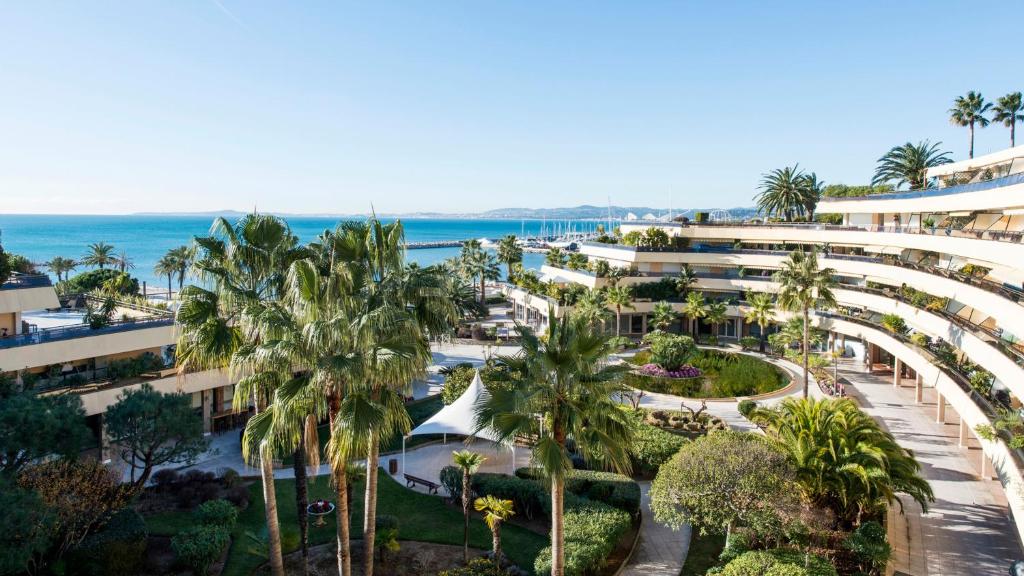 - une vue aérienne sur un complexe avec des palmiers et l'océan dans l'établissement Holiday Inn Nice - Port St Laurent, an IHG Hotel, à Saint-Laurent-du-Var