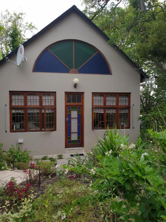 a small white house with a large window at Rozenhof Guest Cottages in George