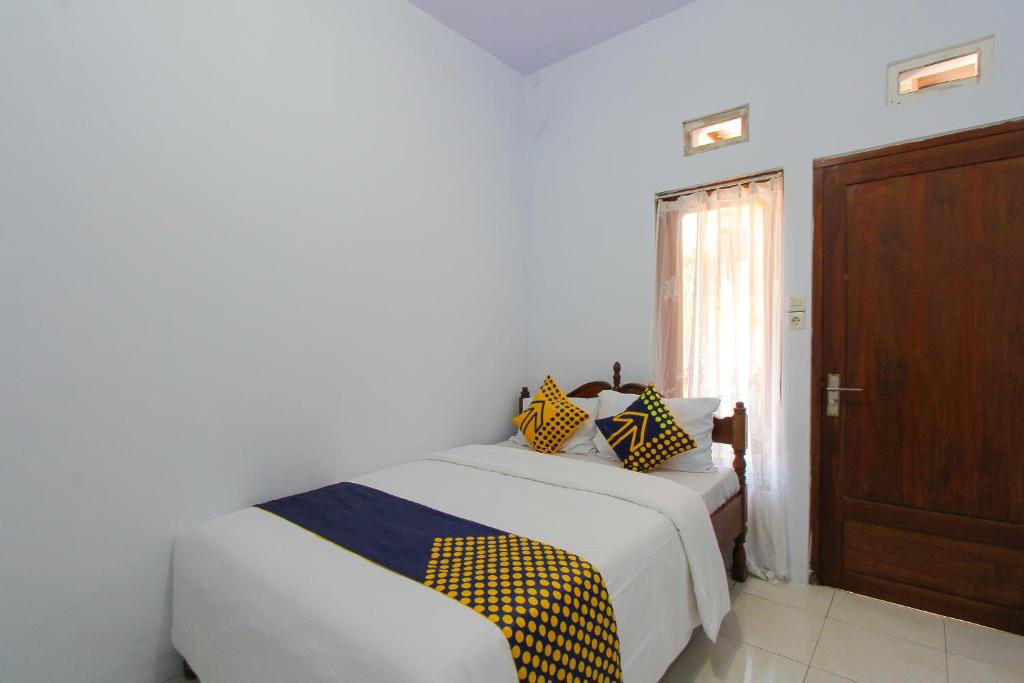 a bedroom with a bed with yellow and blue pillows at SPOT ON 2022 Darman Family Residence Syariah in Banyuwangi