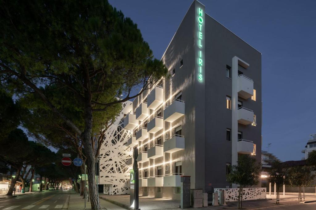 a white building with a green sign on it at Hotel Iris ***S in Lido di Jesolo