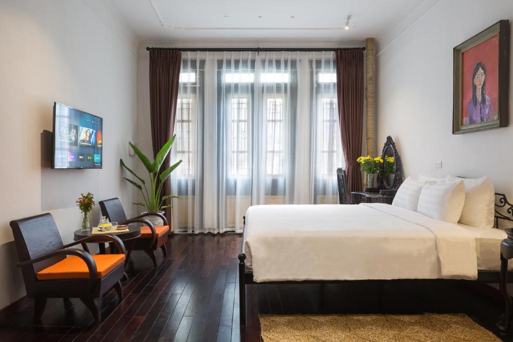 ハノイにあるCentraltique Downtown - Bespoke Colonial House Near Hoan Kiem Lakeのベッド、テーブル、椅子が備わるホテルルームです。