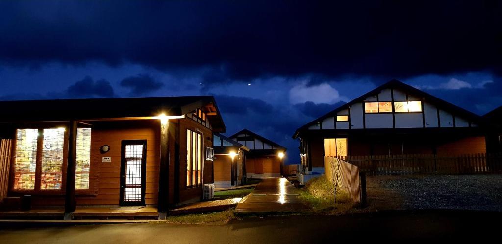 um grupo de casas à noite com luzes em Tsushima Izuhara Pension em Tsushima