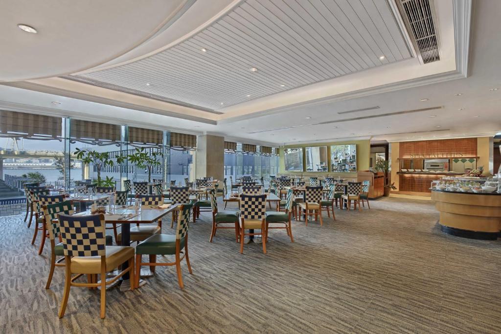 una sala da pranzo con tavoli, sedie e finestre di Harbour Plaza North Point a Hong Kong