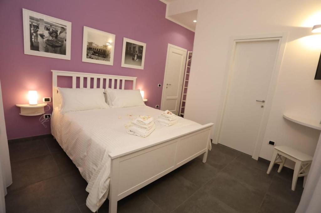 a bedroom with a white bed and a purple wall at Delia Rooms & Gallery in Naples