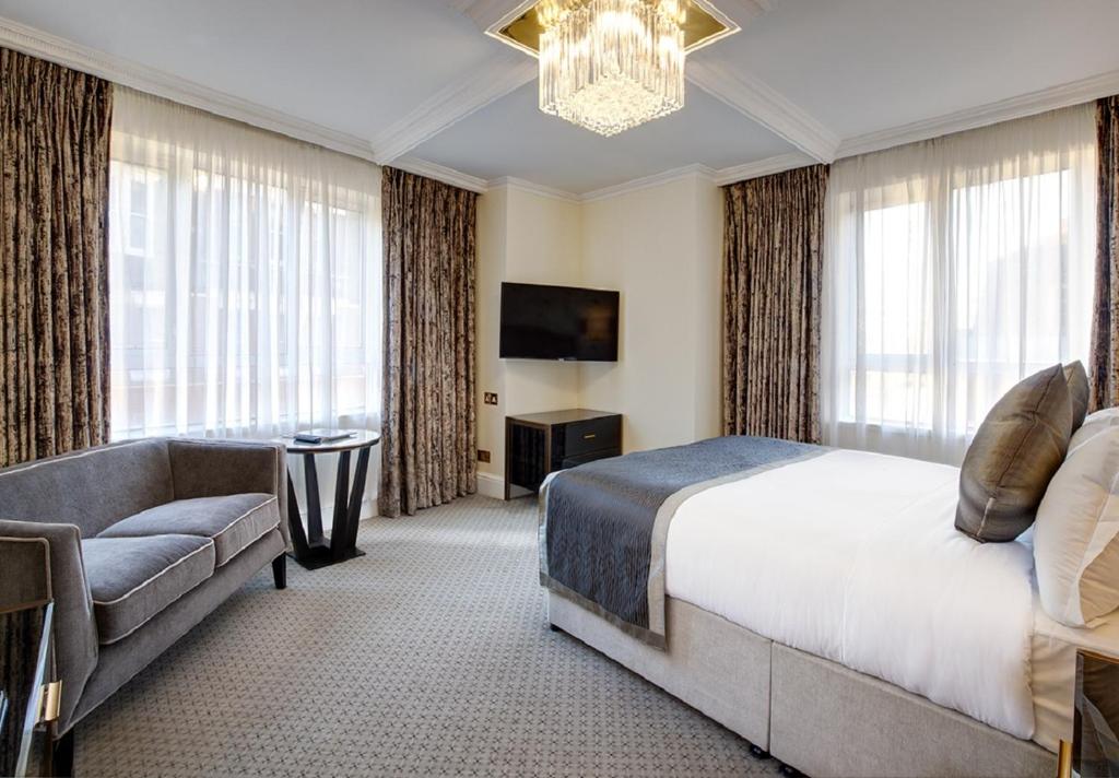 a bedroom with a bed and a couch and a television at The Rathbone Hotel, Fitzrovia in London