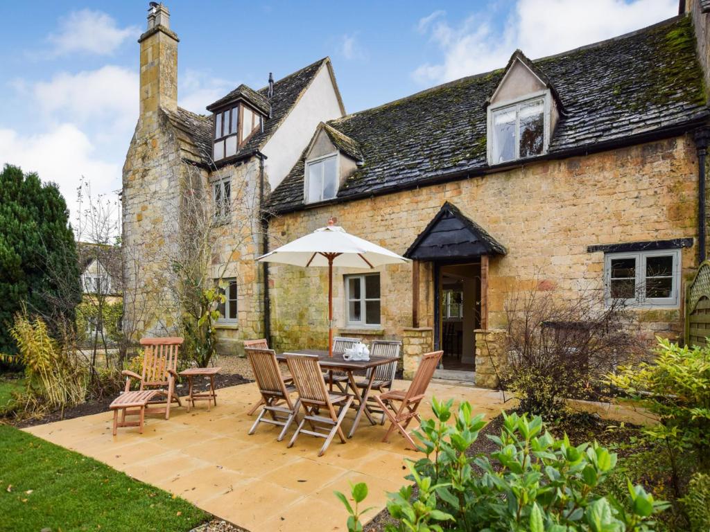 an external view of a house with a table and chairs and an umbrella at Archers in Winchcombe