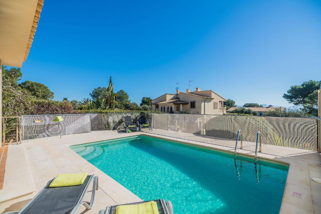 ein Swimmingpool mit Stühlen neben einem Zaun in der Unterkunft Vistamar 5A - Puerto de Alcudia in Alcúdia
