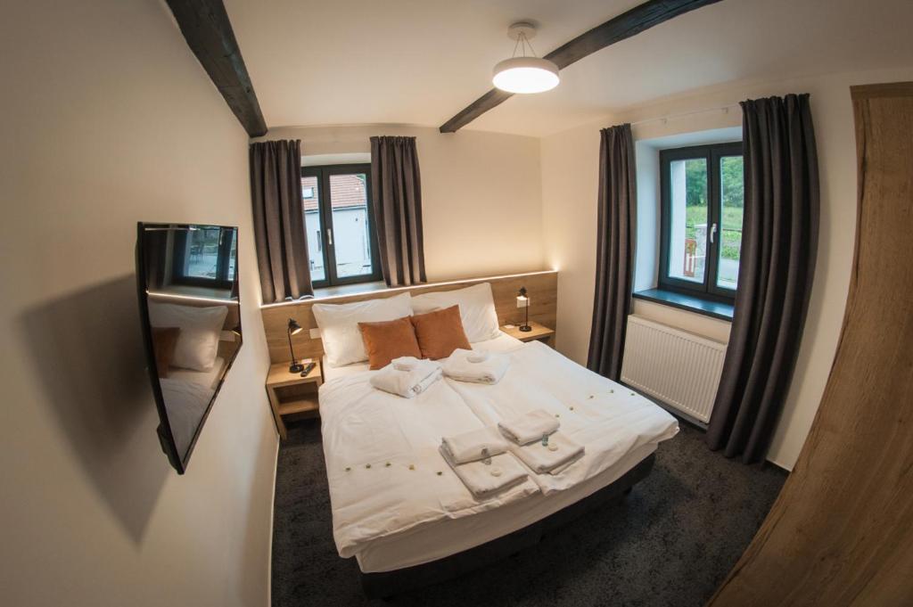 Schlafzimmer mit einem Bett, einem Spiegel und Fenstern in der Unterkunft Resort Orsino in Horní Planá