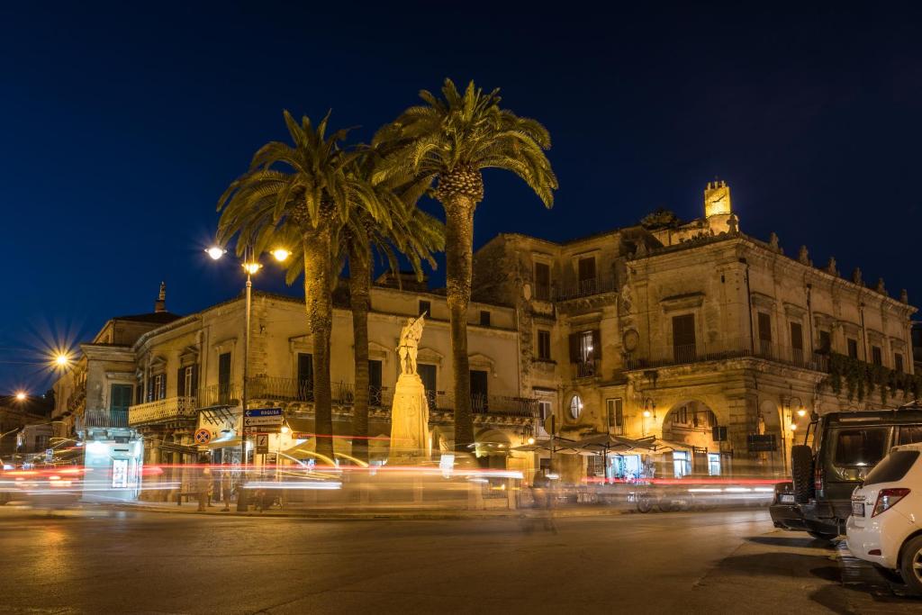 un edificio con palme di fronte ad esso di notte di Le Quattro Colline a Modica