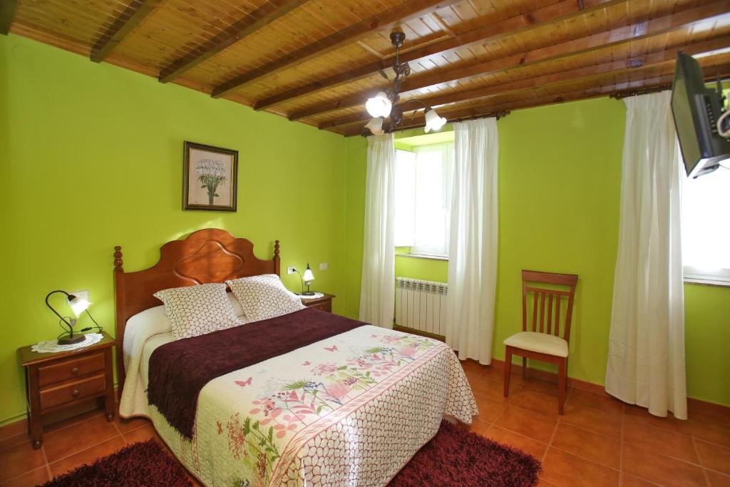 a bedroom with a bed with green walls and a wooden ceiling at Casa Elena Turismo Rural in Reinante