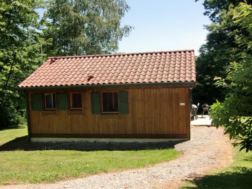 a small wooden cabin with a red roof at Chalet en Auvergne -Pêche in Roumégoux