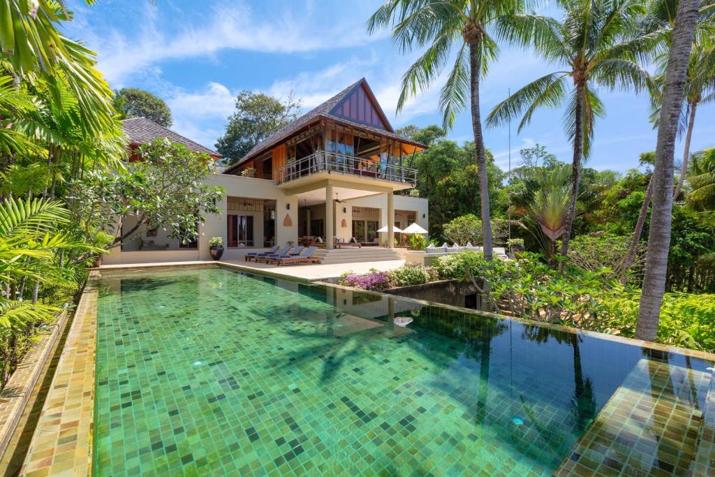 a villa with a swimming pool in front of a house at Villa Praison in Layan Beach