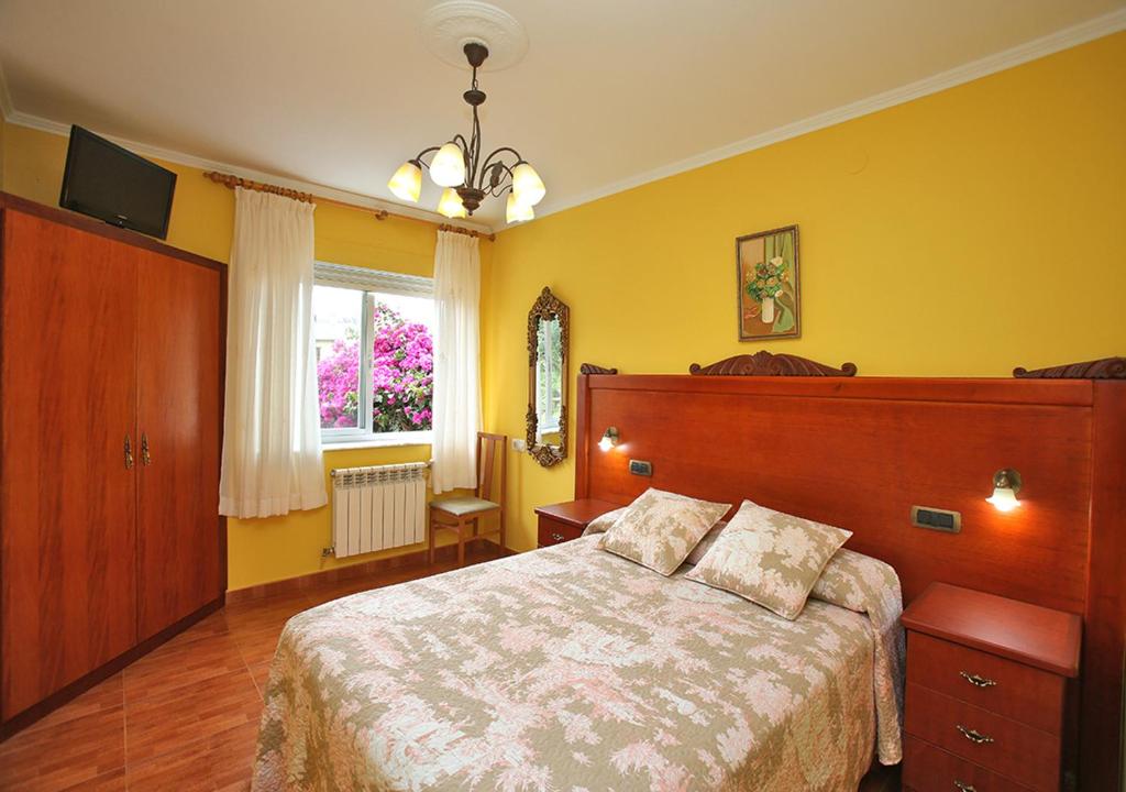 a bedroom with a large bed in a yellow room at Pensión Casa Elena in Reinante