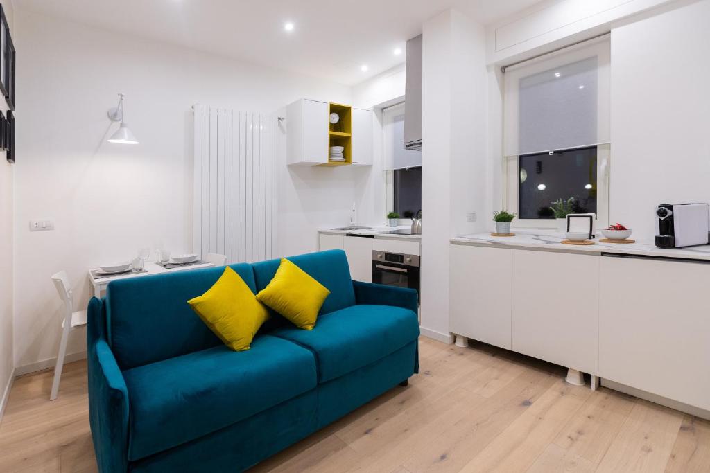 niebieska kanapa z dwoma żółtymi poduszkami w kuchni w obiekcie Apartment Paruta 76 w Mediolanie