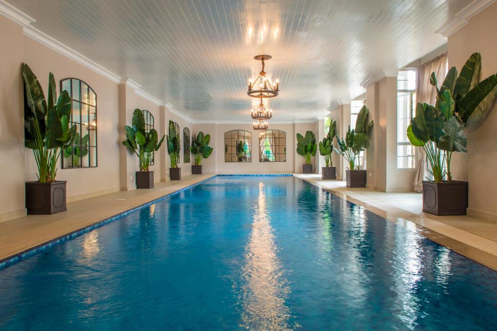 a swimming pool in a room with potted plants at Palacina The Residence & The Suites in Nairobi