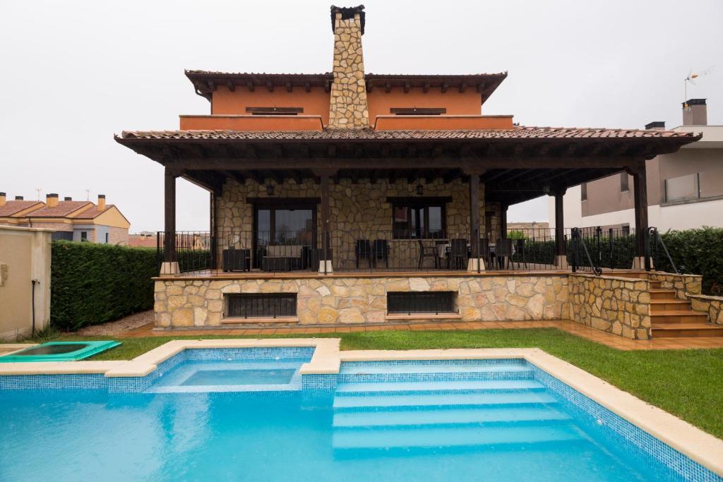 una casa con piscina frente a un edificio en LA CASA DE ANVER, en La Lastrilla