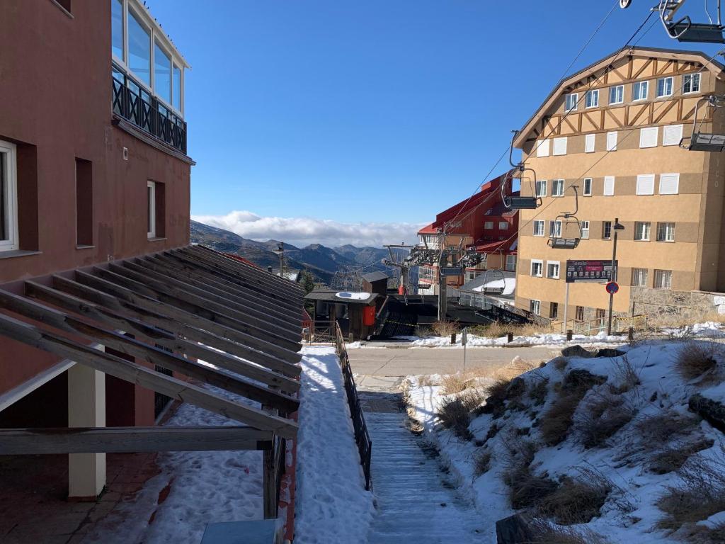 a building with snow on the ground next to a building at Apartamentos Sabica in Sierra Nevada