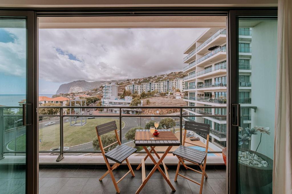 a balcony with a table and chairs and a view of the ocean at Cozy T2 with Ocean View in Funchal