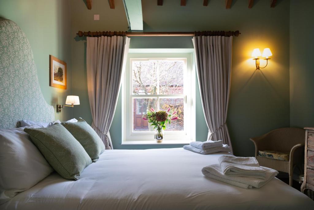 1 dormitorio con 1 cama blanca y ventana en The Horse and Groom Inn en Chichester