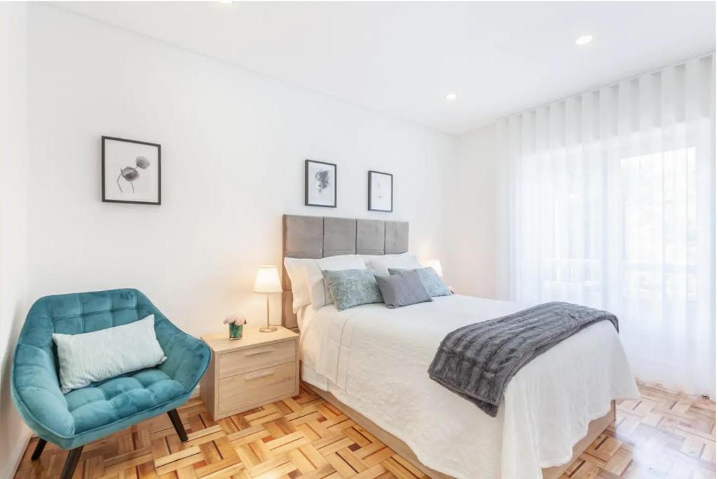 a bedroom with a bed and a blue chair at Old Market Apartment in Guimarães
