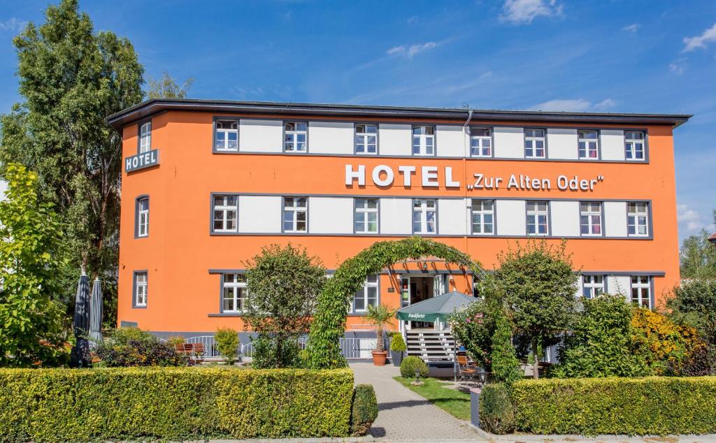 ein orangefarbenes Hotel mit einem Bogen davor in der Unterkunft Frankfurt-Oder,Hotel & Restaurant ,,Zur Alten Oder" in Frankfurt (Oder)