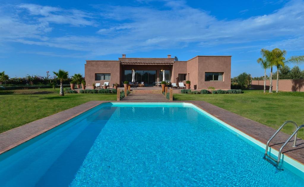 a villa with a swimming pool in front of a house at DOMAINE VILLA PRIVE in Marrakesh