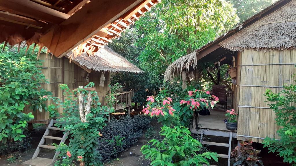 een klein huis met een rieten dak en planten bij Tribal Village Homestay & Trekking in Banlung