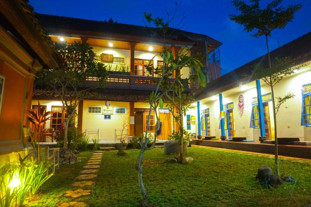 een huis met een tuin ervoor in de nacht bij Damuh Guest House in Ubud