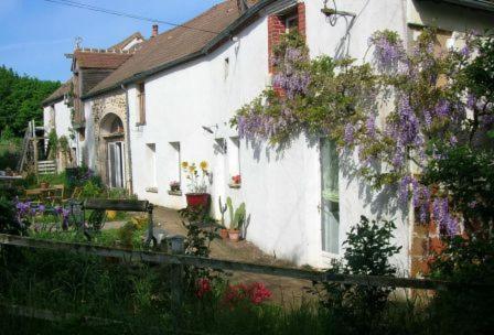 a white house with purple flowers on the side of it at Chambre d'hôtes Ermitage Saint Romble in Crézancy