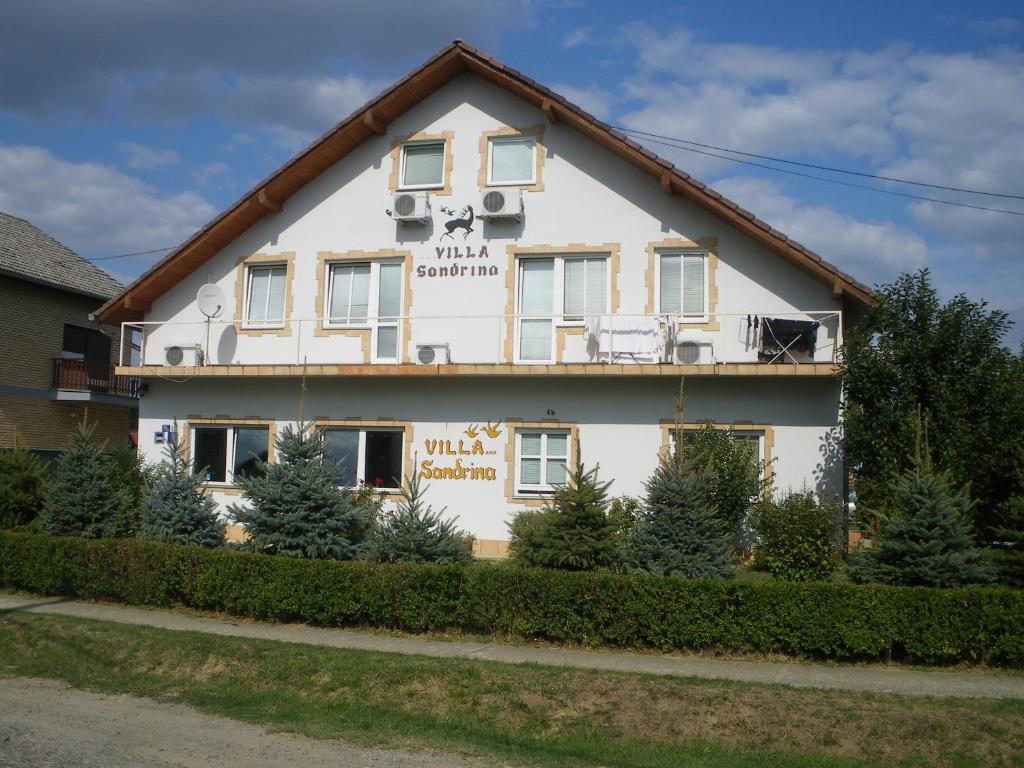 une grande maison blanche avec des arbres devant elle dans l'établissement B&B Sandrina, à Bilje