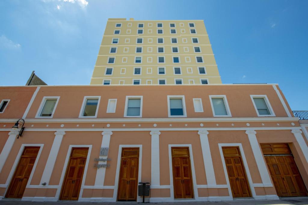 a building with a tall building in the background at Holiday Inn Express - Merida Centro, an IHG Hotel in M&eacute;rida