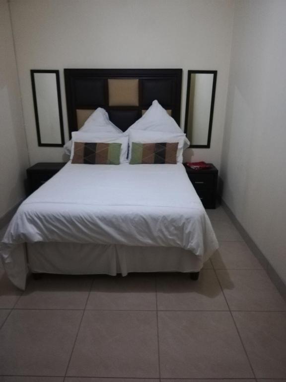 a bedroom with a bed with white sheets and pillows at Rocky Ridge Guest House 2 SELF CATERING - No Alcohol allowed in Roodepoort