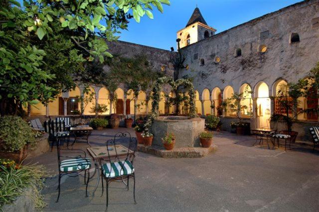 an outdoor patio with tables, chairs, and a clock at Hotel Luna Convento in Amalfi
